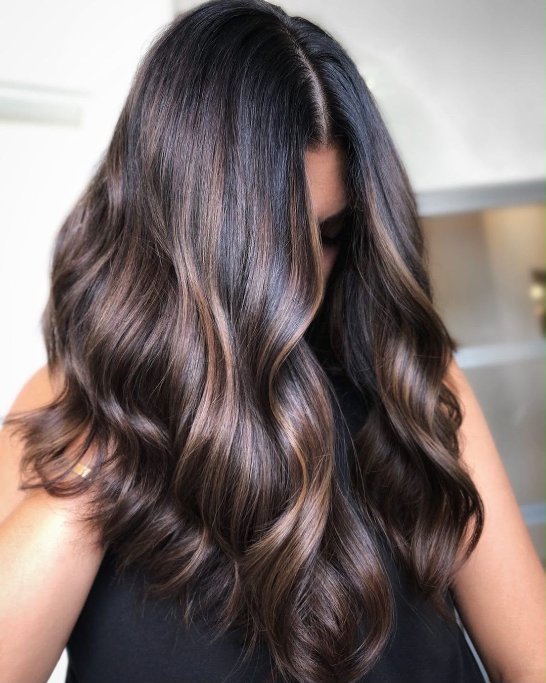 Glossy brunette waves with caramel ribbons of dimension